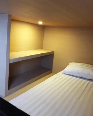 a small bedroom with a bed and a shelf at XOXO Kuta Legian Hostel in Legian
