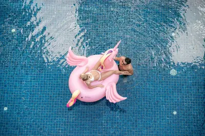 a man riding a pink unicorn in a swimming pool at EDEN Hotel Kuta Bali in Kuta