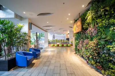 a lobby with blue chairs and a wall of plants at EDEN Hotel Kuta Bali in Kuta
