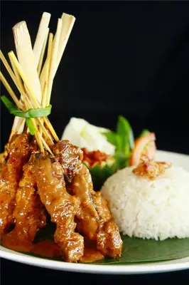 a plate of food with chicken and rice and chopsticks at b Hotel Bali & Spa in Denpasar
