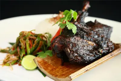a plate of food with a piece of meat and vegetables at b Hotel Bali & Spa in Denpasar