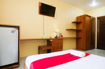 a bedroom with a bed and a desk and a tv at RedDoorz @ Kerta Dalem Sidakarya in Denpasar