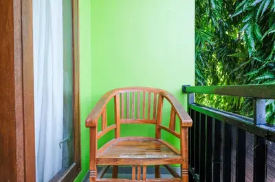 a wooden chair sitting on top of a balcony at RedDoorz @ Kerta Dalem Sidakarya in Denpasar