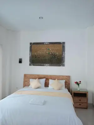 a bedroom with a white bed with a picture on the wall at Adijaya homestay in Seminyak
