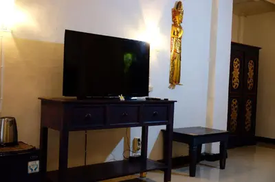 a television on top of a dresser with a stool at Puri Cendana Resort Bali in Seminyak