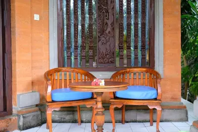 two chairs and a table with a wooden table and a door at Puri Cendana Resort Bali in Seminyak