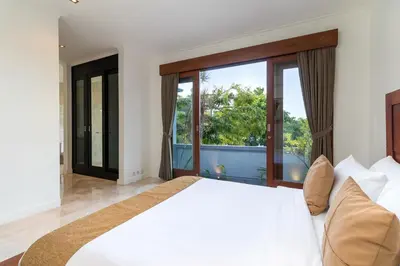 a bedroom with a large bed and a large window at Villa Lalang Temu in Jimbaran