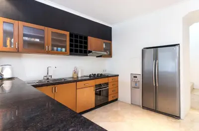 a kitchen with a stainless steel refrigerator and wooden cabinets at Villa Lalang Temu in Jimbaran