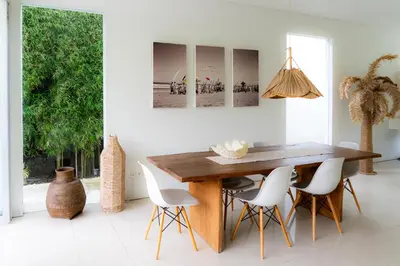 a dining room with a wooden table and white chairs at Villa Capil in Seminyak