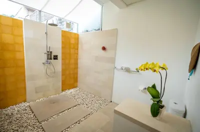 a bathroom with a shower and a vase of flowers at Villa Capil in Seminyak