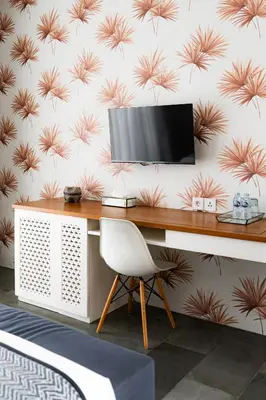 a desk with a television on a wall with pink flowers at Villa Capil in Seminyak