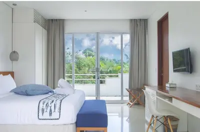 a bedroom with a bed and a desk and a window at Villa Capil in Seminyak