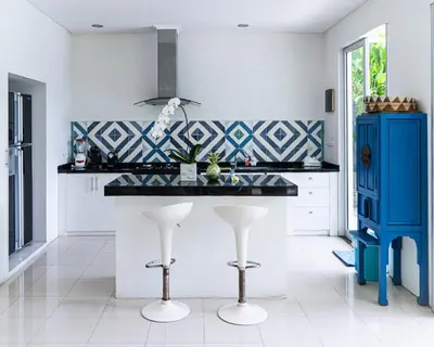a kitchen with a counter with stools and a blue cabinet at Villa Capil in Seminyak