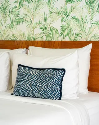 a bed with white pillows and a wallpaper at Villa Capil in Seminyak