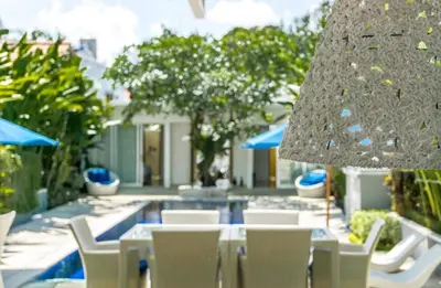 a table with white chairs and a large umbrella at Villa Capil in Seminyak