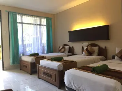 a hotel room with four beds and a large window at Bakung Beach Resort in Kuta