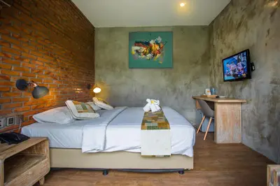 a bedroom with a bed and a brick wall at Bali Breezz Hotel in Jimbaran