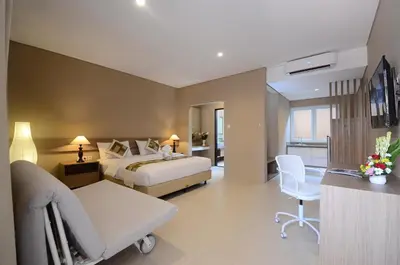 a large hotel room with a bed and a chair at Bali Breezz Hotel in Jimbaran