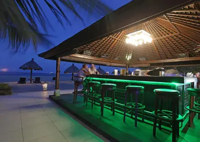 a bar on the beach with people sitting at it at Peninsula Beach Resort in Nusa Dua