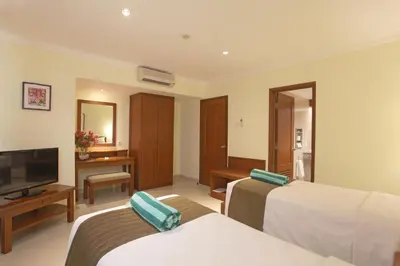 a hotel room with two beds and a television at Peninsula Beach Resort in Nusa Dua