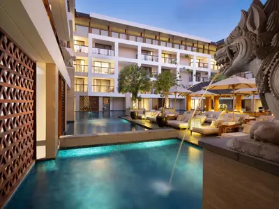 a hotel with a swimming pool in front of a building at Royal Suites at The Bandha in Legian