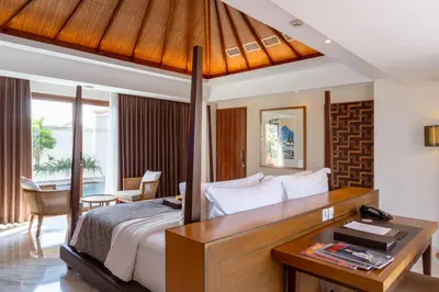 a bedroom with a large bed with a desk and a desk at Royal Suites at The Bandha in Legian
