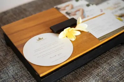 a wedding invitation in a wooden box with a yellow flower at Royal Suites at The Bandha in Legian