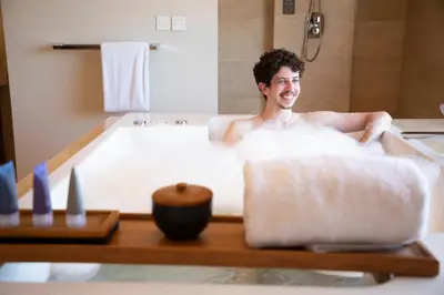 a man sitting in a bath tub with a candle at Royal Suites at The Bandha in Legian