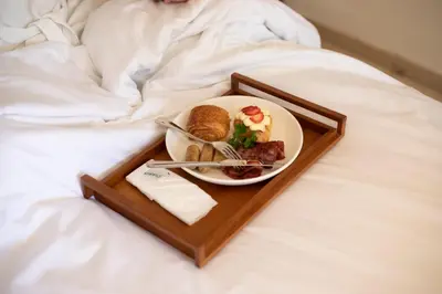a plate of food on a tray on a bed at Royal Suites at The Bandha in Legian