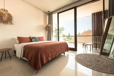 a bedroom with a bed and a large window at Pelangi 148 Beach Suites in Seminyak
