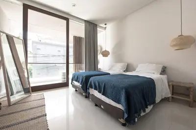 a bedroom with two beds and a large window at Pelangi 148 Beach Suites in Seminyak