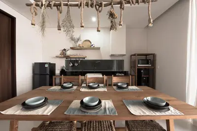 a dining room with a wooden table and a kitchen at Pelangi 148 Beach Suites in Seminyak