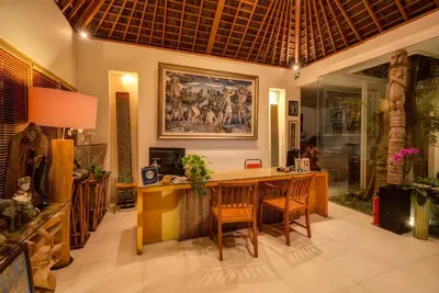 a living room with a table and chairs and a painting at Villa Bali Asri Batubelig in Seminyak
