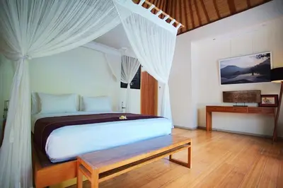 a bedroom with a bed with white curtains and a table at Villa Bali Asri Batubelig in Seminyak