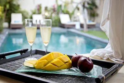 a tray with glasses of champagne and fruit next to a swimming pool at Villa Star in Seminyak