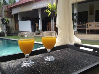 two glasses of orange juice sitting on a table next to a pool at Villa Star in Seminyak