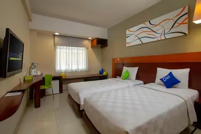 a hotel room with two beds and a television at PrimeBiz Hotel Kuta in Kuta