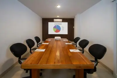 a conference room with a long wooden table and chairs at PrimeBiz Hotel Kuta in Kuta