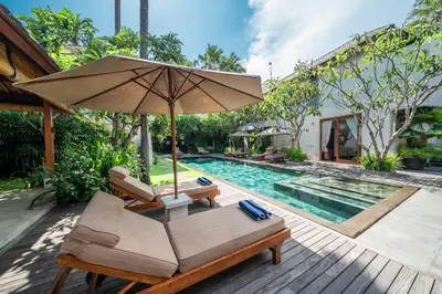an umbrella and chairs next to a swimming pool at Villa Rubina - Luxury Pool Villa in Batu Belig Next to the Beach! in Seminyak