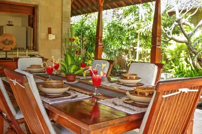 a wooden table with plates and glasses on it at Villa Plawa Asri in Seminyak