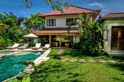 a villa with a swimming pool and a house at Hevea Villas in Seminyak