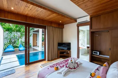 a bedroom with a bed and a tv and a pool at Bali Vilaasee in Seminyak