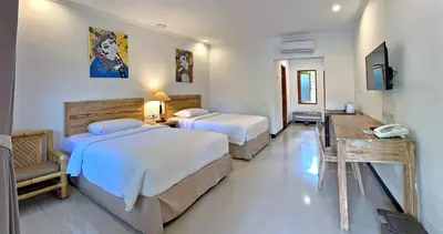 a hotel room with two beds and a television at Sanur Lodge in Sanur