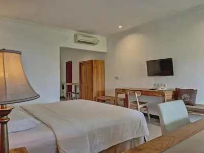 a bedroom with a bed and a desk and a television at Sanur Lodge in Sanur