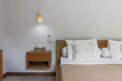 a bedroom with a bed with white pillows and a night stand at Balinea Holiday Home in Kerobokan