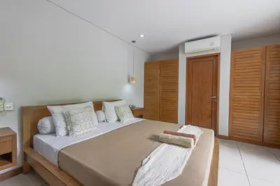 a bedroom with a large bed and wooden cabinets at Balinea Holiday Home in Kerobokan