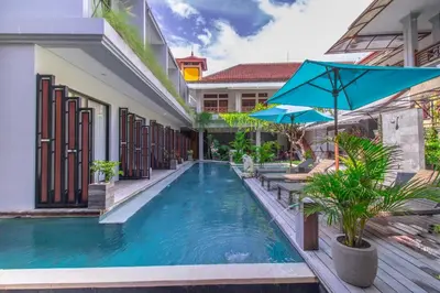 a swimming pool with an umbrella next to a building at Gemini Star Hotel Kuta in Kuta