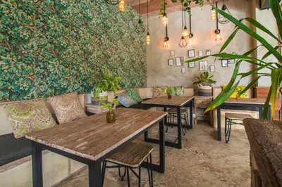 a restaurant with tables and chairs and plants at Gemini Star Hotel Kuta in Kuta