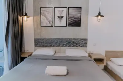 a bedroom with a white bed with three pictures on the wall at Gemini Star Hotel Kuta in Kuta