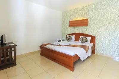 a bedroom with a wooden bed in a room at Ayu Lili Garden Hotel Kuta in Kuta